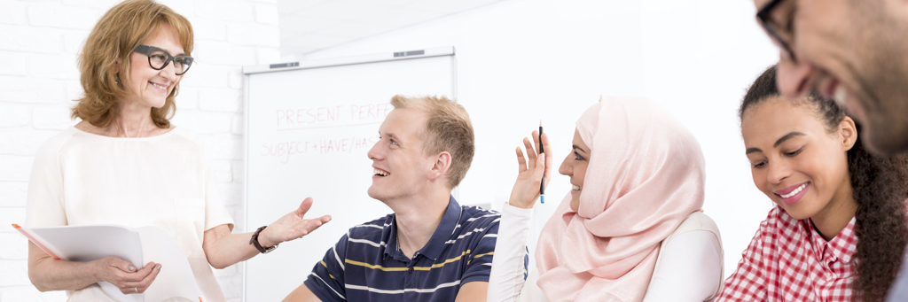 happy participants of a language course with their teacher in classroom